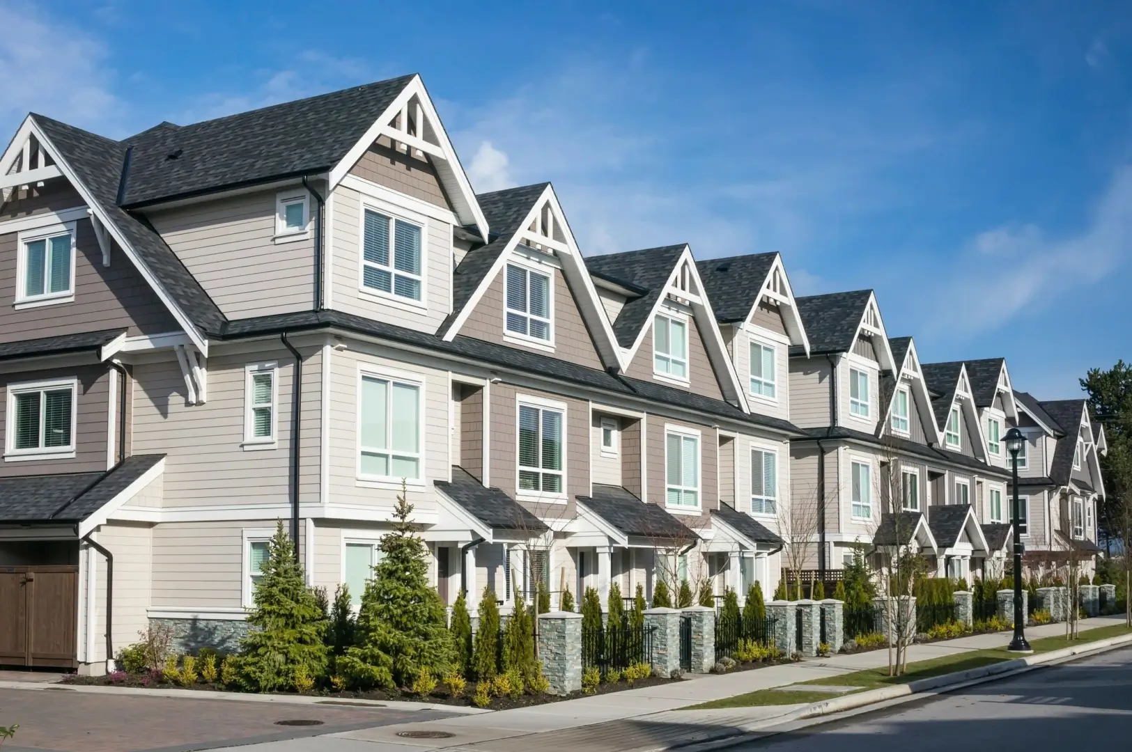 A row of houses with trees in front.