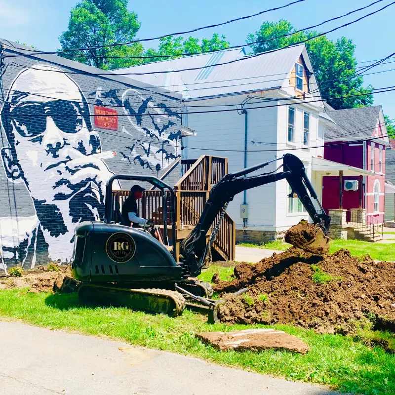 A man digging in the dirt near a mural.